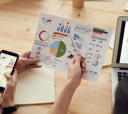 Team members analyze charts during a business meeting with laptops and smartphones.